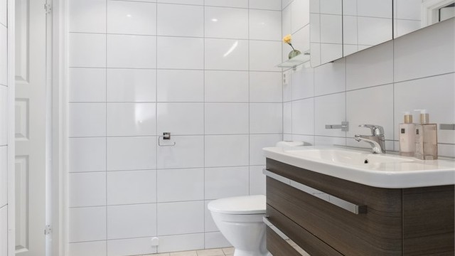 Vegghengt servantmøbel med skuffer, speilskap og integrert belysning.