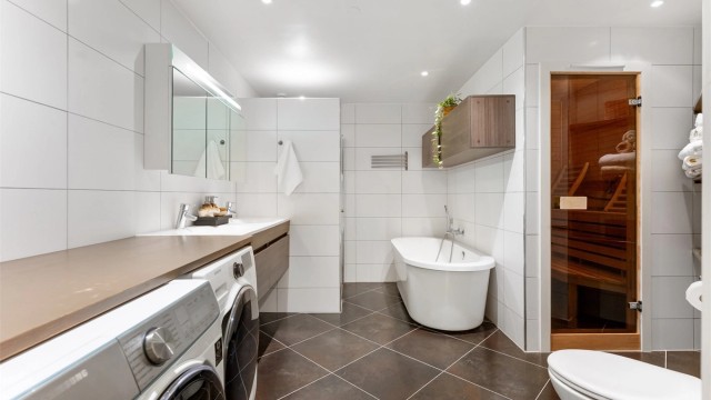Pent baderom fra 2013 med fliser på gulv med gulvvarme, fliser på vegger og malt himling med downlights