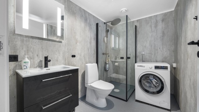 Badet har elektriske varmekabler i gulvet, baderomsplater på veggene og opplegg for vaskemaskin.
