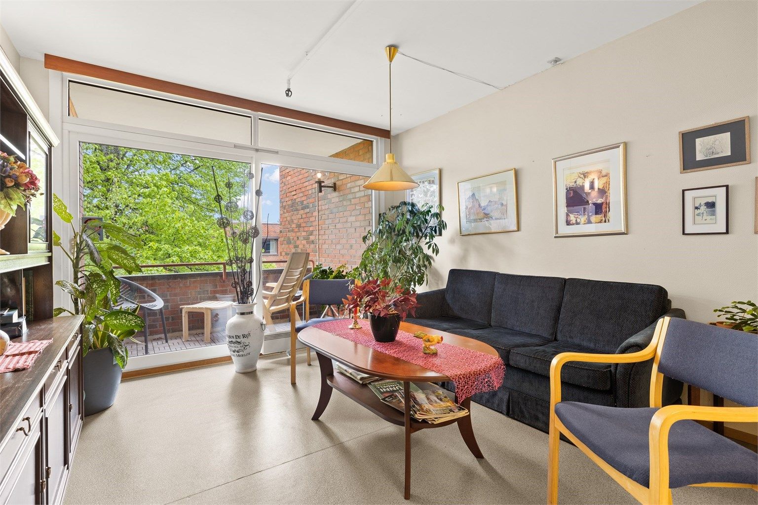 Felles stue til fri bruk for beboere og deres gjester, med balkong og hyggelig utsyn mot atriet