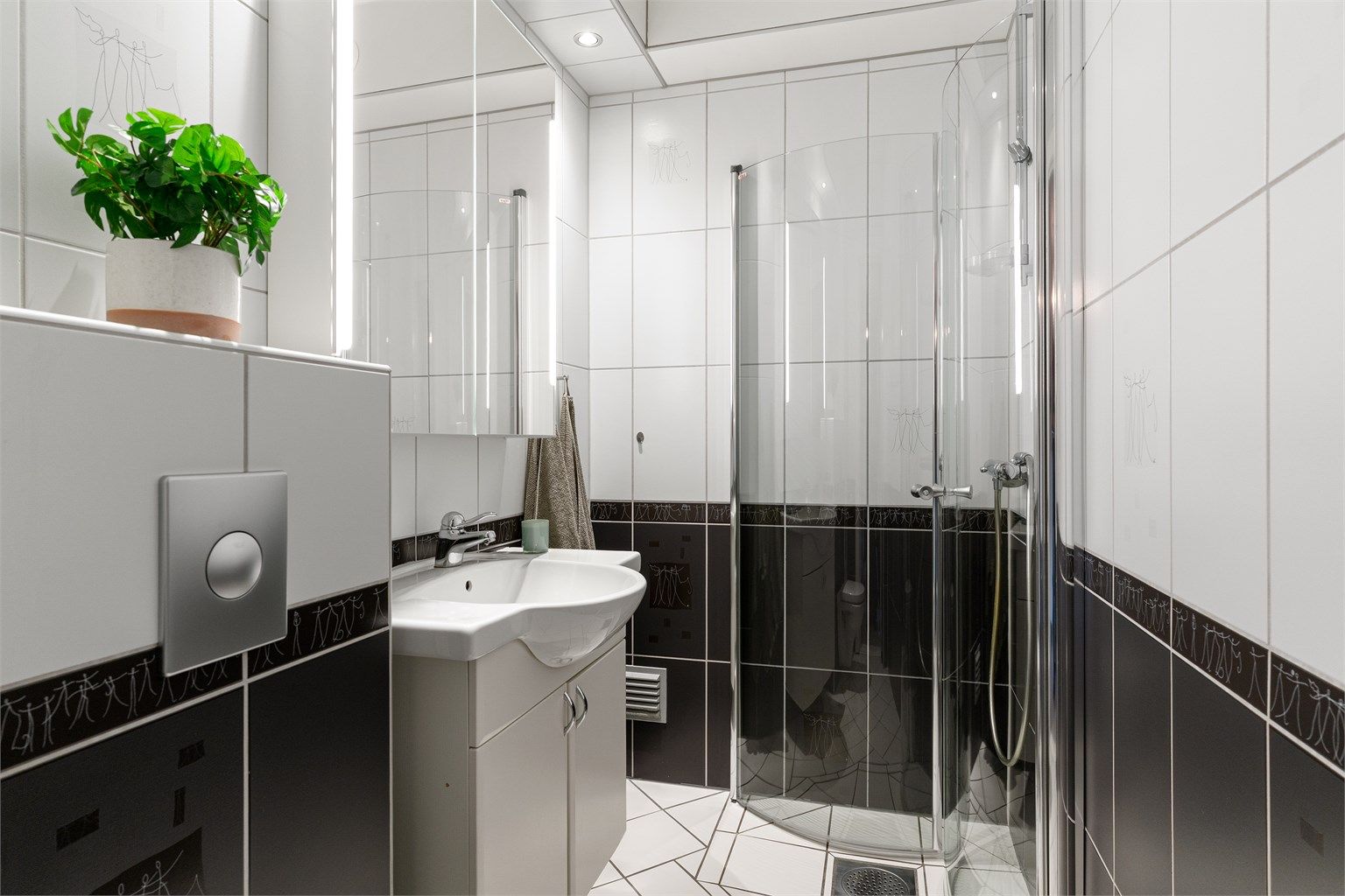 Badet er flislagt og har elektrisk gulvvarme for ekstra komfort. Innredningen består av vegghengt servantskap med servant, samt et praktisk speilskap med belysning over. 