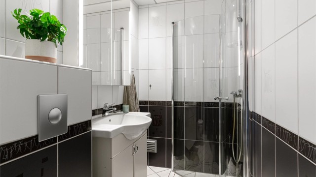 Badet er flislagt og har elektrisk gulvvarme for ekstra komfort. Innredningen består av vegghengt servantskap med servant, samt et praktisk speilskap med belysning over.