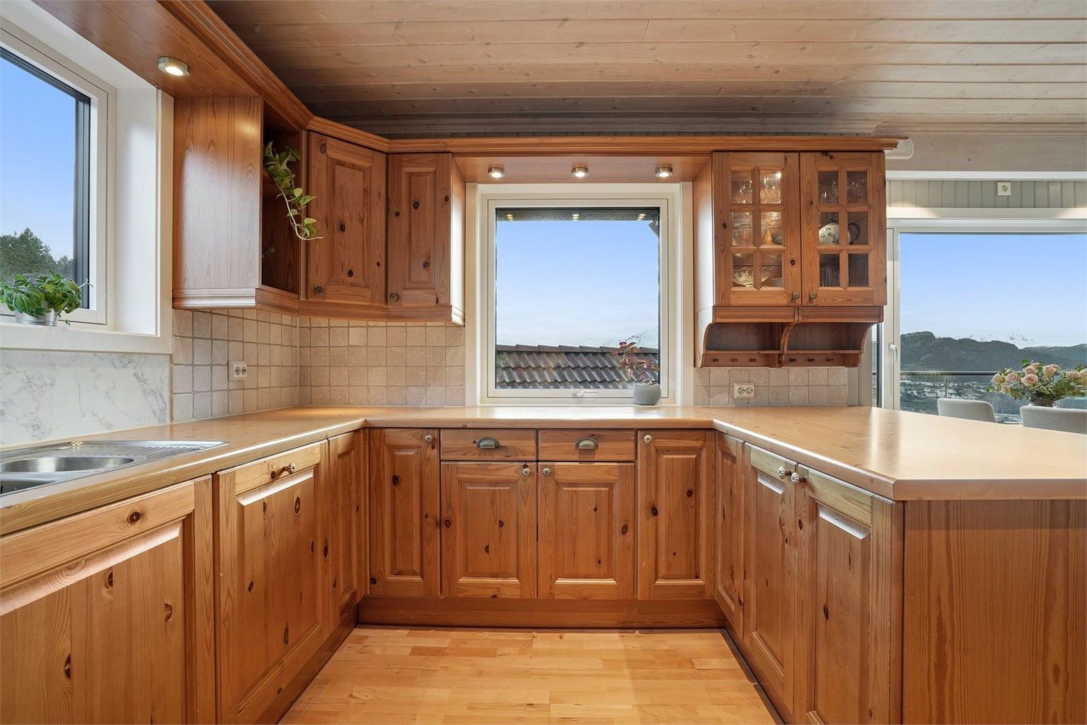 Kjøkkeninnredning med profilerte fronter og kjøkkenhalvøy mot spisedel. Godt med naturlig lysinnslipp fra vinduer.