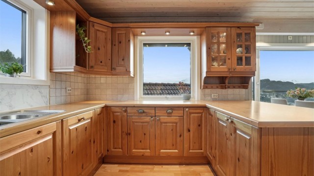 Kjøkkeninnredning med profilerte fronter og kjøkkenhalvøy mot spisedel. Godt med naturlig lysinnslipp fra vinduer.