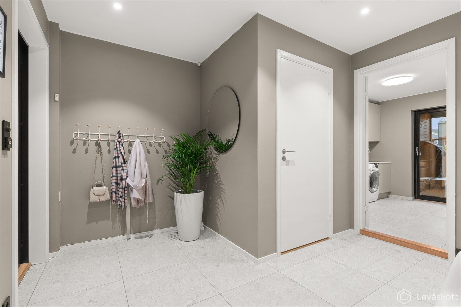 En lys og innbydende entré med store 60x60 fliser og downlights i himlingen.