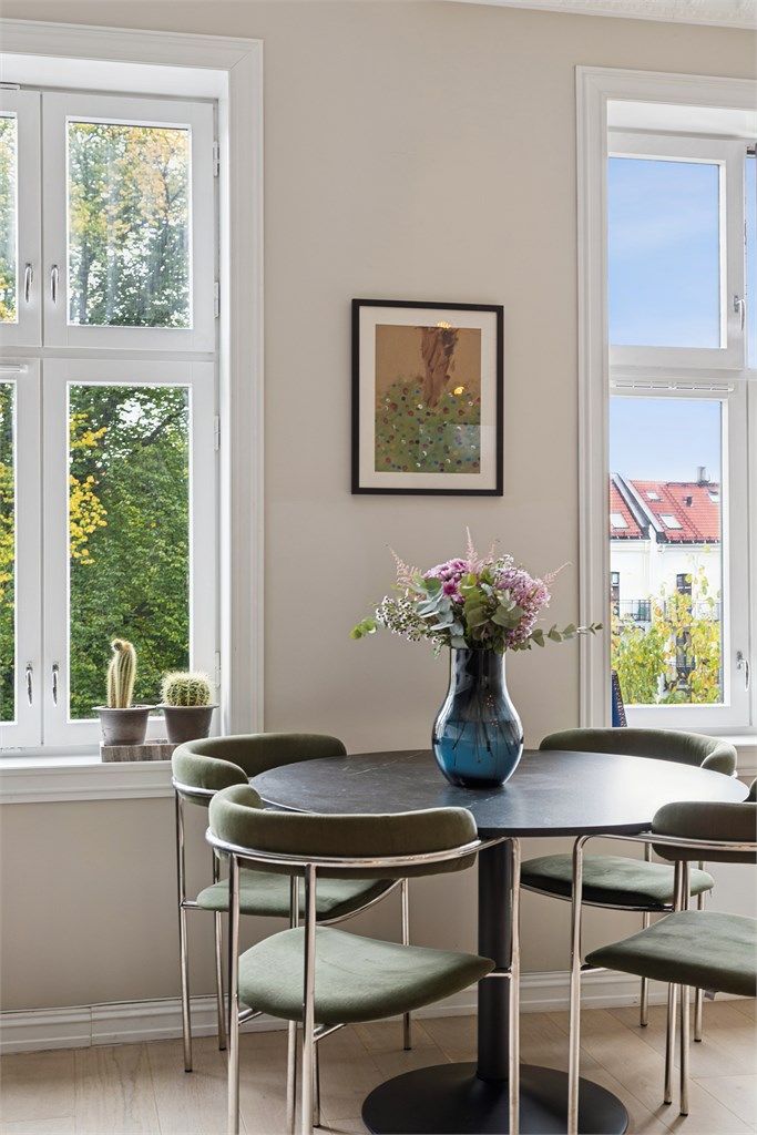 Spiseplassen er plassert ved store vindusflater med utsikt mot grønne omgivelser.