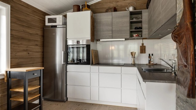 Mellom kjøkkenbenk og overskapene, er det laminert flisplate, som gjør det enkelt å holde veggflatene ren. Legg og merke til stikkontakter og belysning under overskapene