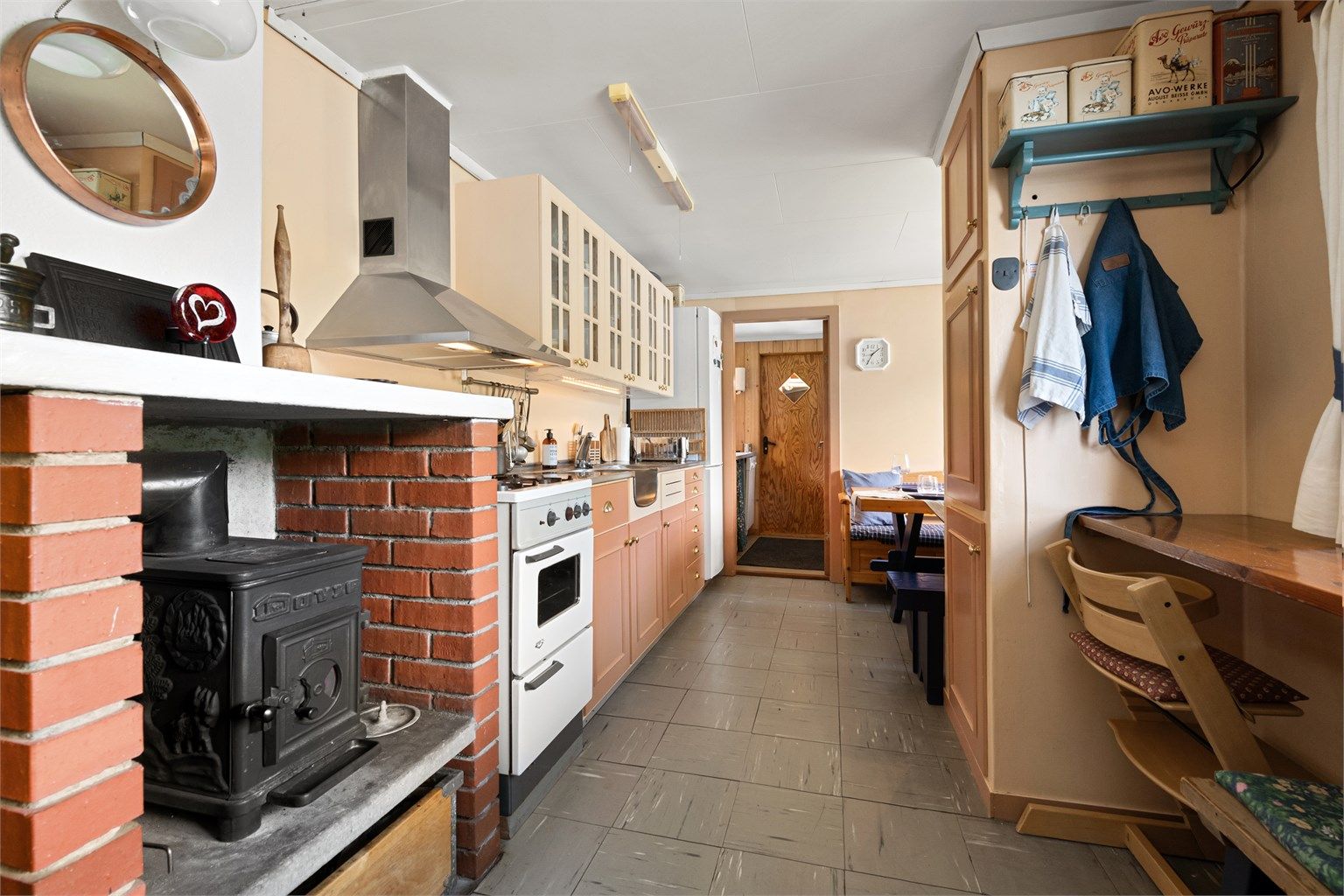 Frittstående gasskomfyr og kjøl/fryseskap på kjøkkenet. Oppvaskmaskin plassert til tilhørende vaskerom/grovkjøkken