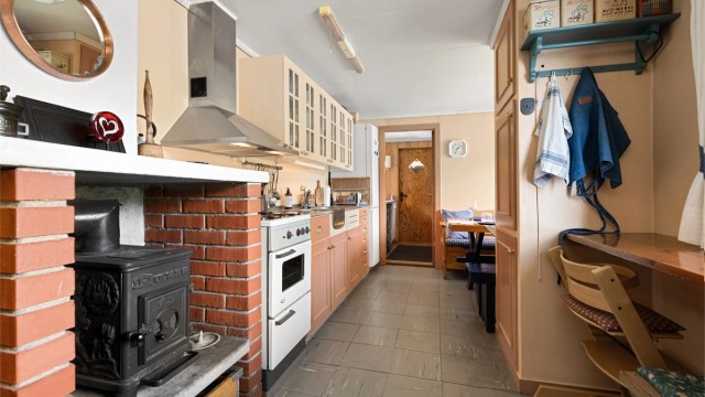 Frittstående gasskomfyr og kjøl/fryseskap på kjøkkenet. Oppvaskmaskin plassert til tilhørende vaskerom/grovkjøkken