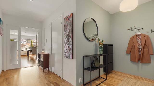 Romslig gang med dør som skiller to av soverommene og bad fra stue/kjøkken