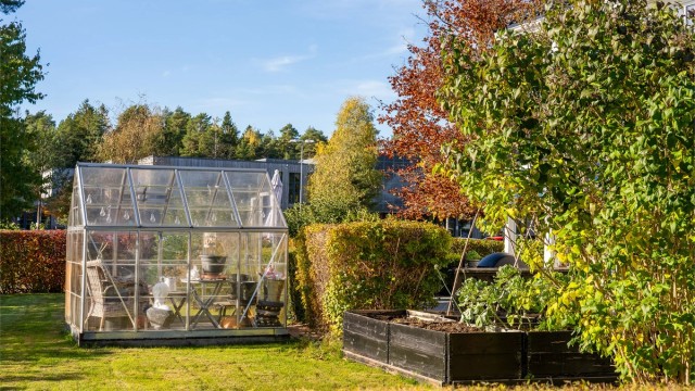 Drivhuset er plassert like ved plantekassene i hagen.
