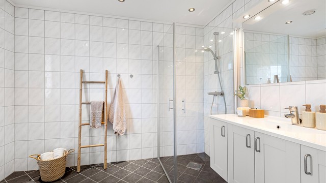 Flislagt bad i 1. etasje med gulvvarme, downlights og dusjhjørne med innfellbare glassdører.
