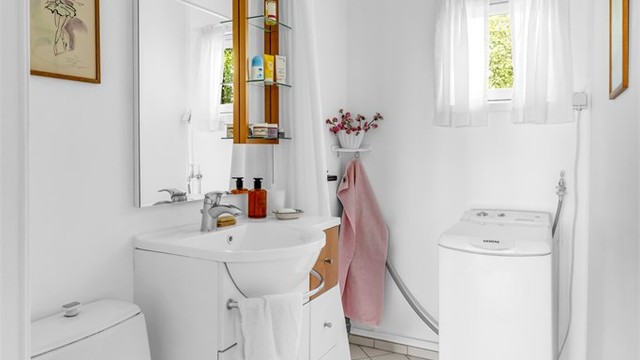 Flislagt bad med varmekabler, dusj, toalett og opplegg for vaskemaskin på øvre plan.
