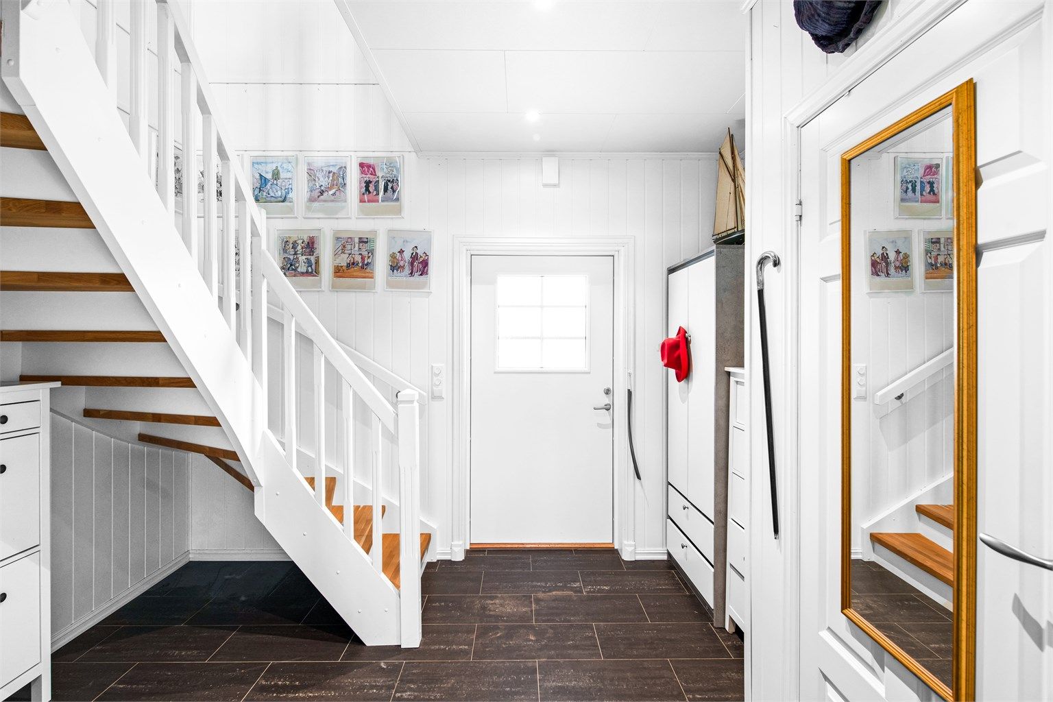 En romslig hall ønsker deg velkommen. Her er det praktiske fliser med varmekabler i gulv, samt gode muligheter for garderobe og lagring.