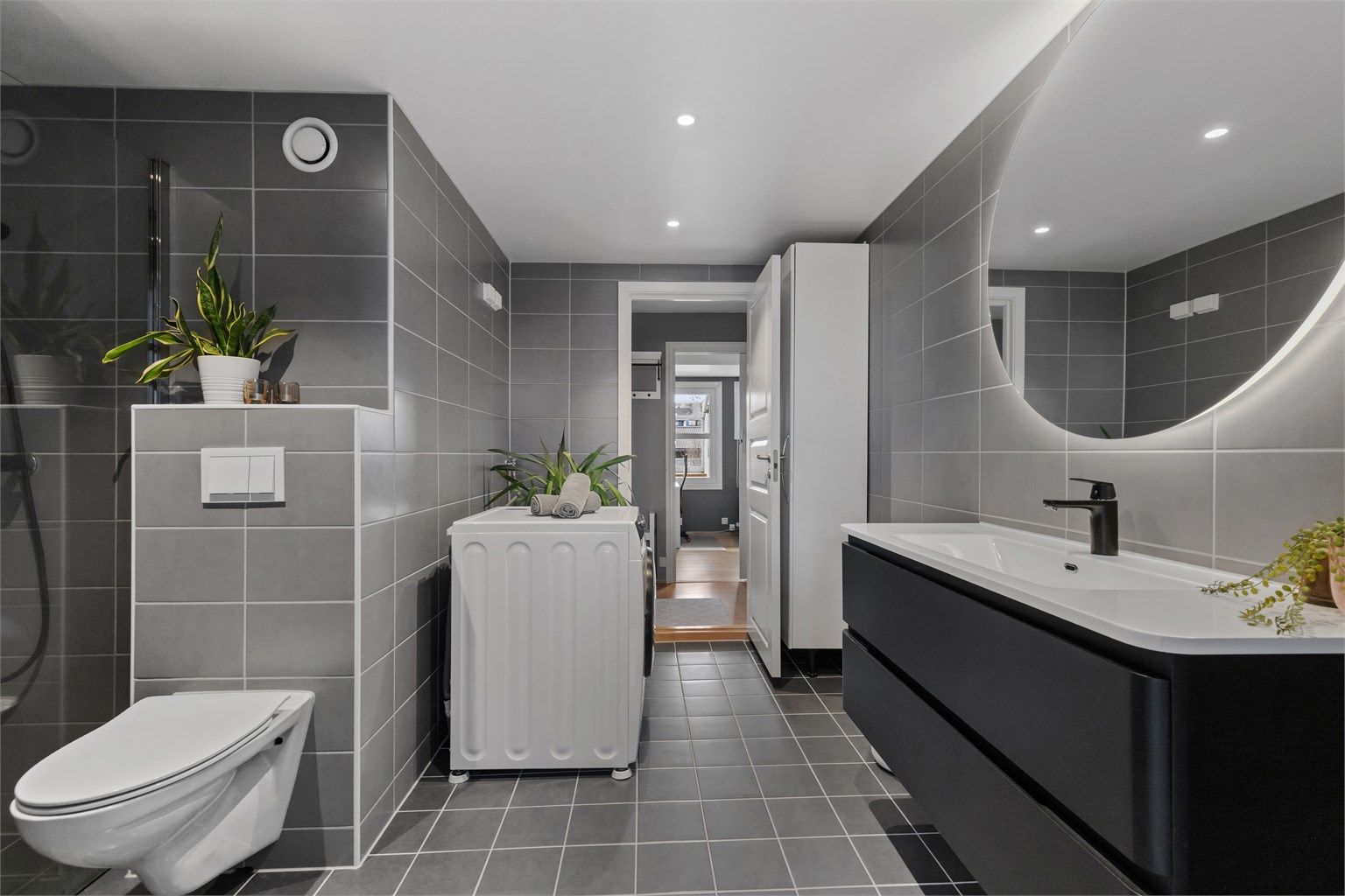 Delikat, helfliset bad med moderne innredning, vegghengt toalett og varme i gulvet.