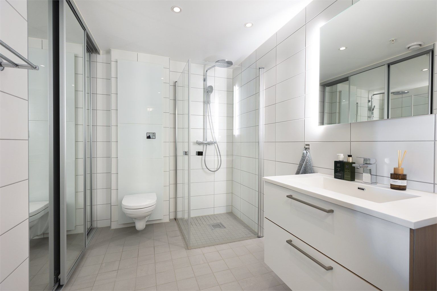 Badet har flislagte overflater, gulvvarme og downlights i taket.