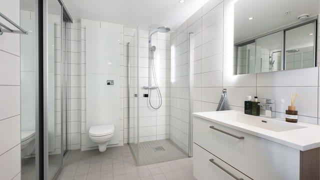 Badet har flislagte overflater, gulvvarme og downlights i taket.