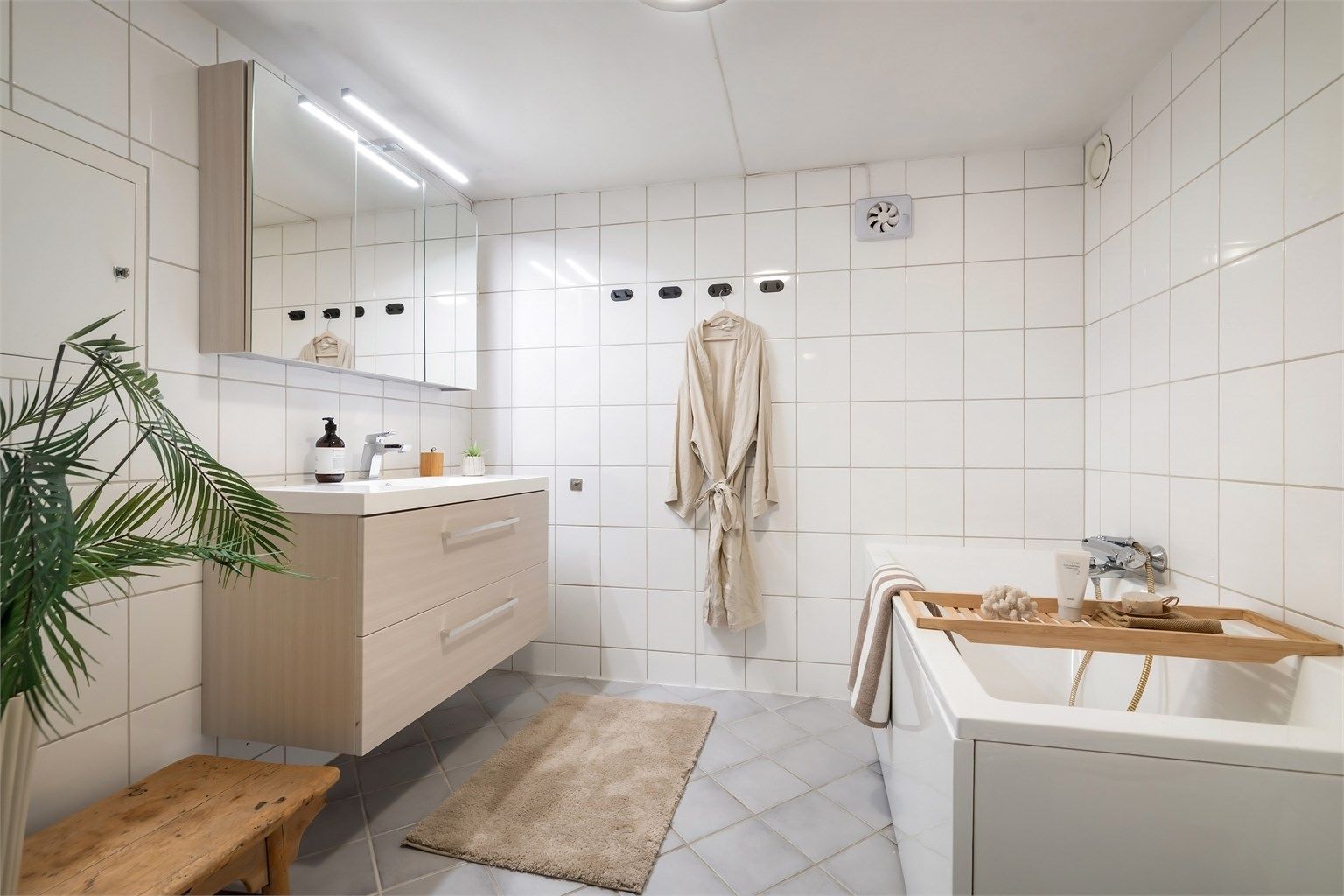 Badet har innredning med heldekkende servant og overskap med speil.