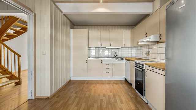 Kjøkkeninnredningen har over- og underskap samt nisjer for frittstående hvitevarer.
