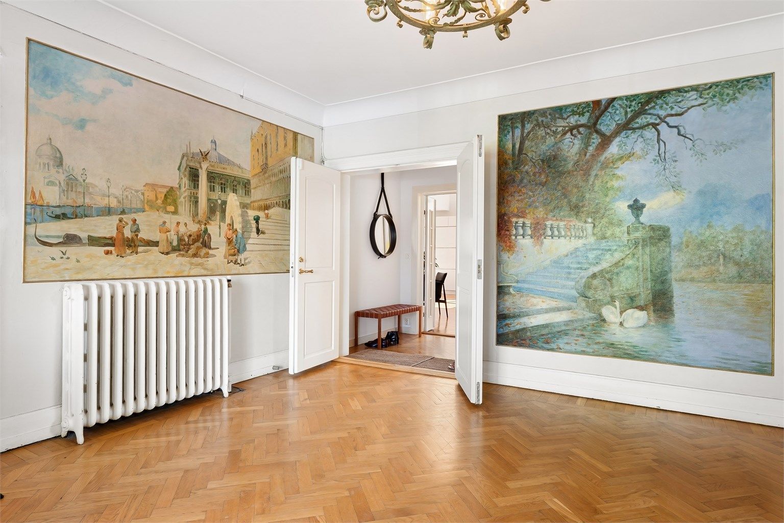 Adkomst til leiligheten skjer via en representativ felles hall med veggmalerier og klassisk fiskebensparkett.