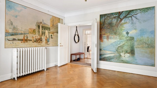 Adkomst til leiligheten skjer via en representativ felles hall med veggmalerier og klassisk fiskebensparkett.