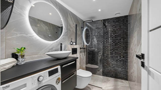 Badet ble rehabilitert i 2021 og har et moderne og stilrent uttrykk med gjennomgående flislagte overflater, gulvvarme og tidsriktige detaljer.