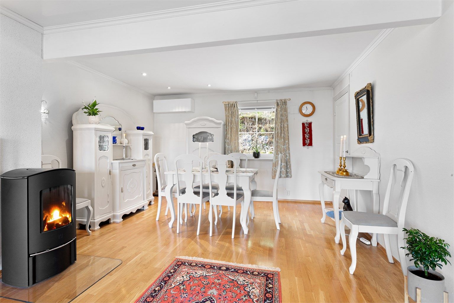 Frittstående peisovn med glassplate på gulv, pent plassert i midten av rommet.