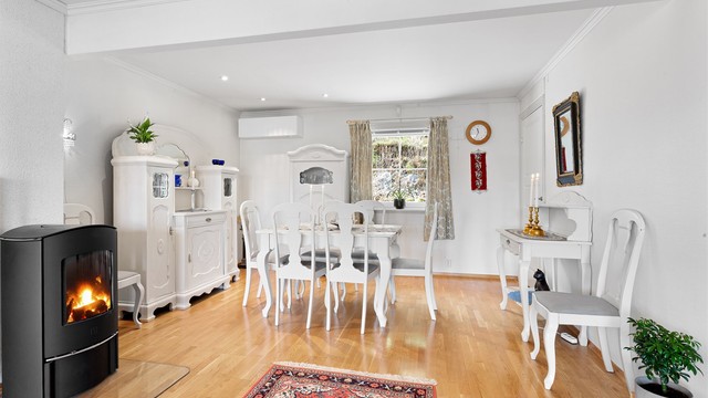 Frittstående peisovn med glassplate på gulv, pent plassert i midten av rommet.