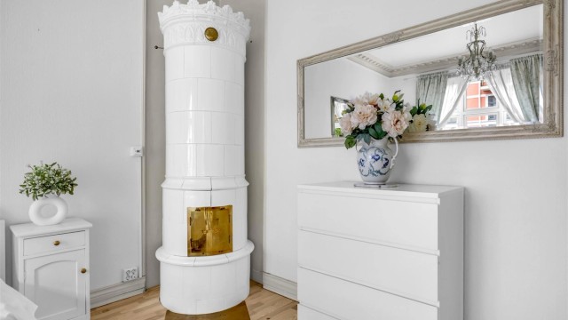 I hjørnet av rommet er det montert en kakkelovn som tilfører rommet karakter samtidig som den gir god og lun varme.
