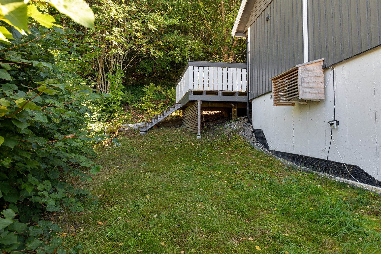 Skrånende tomt opparbeidet med plenareal og trapp opp til terrassen.