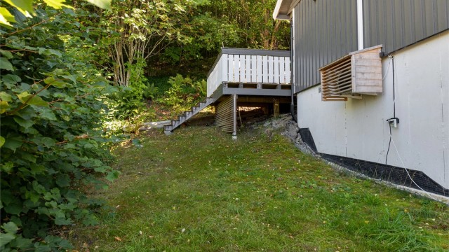 Skrånende tomt opparbeidet med plenareal og trapp opp til terrassen.