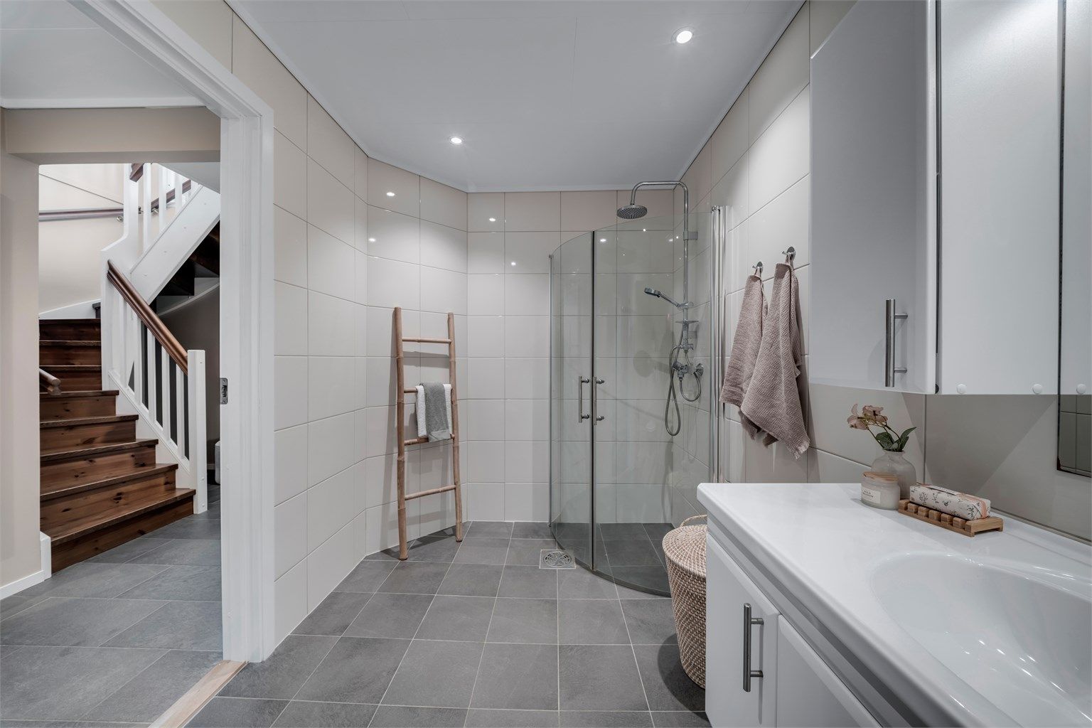 Flislagt bad med behagelig belysning fra downlights og et stilrent dusjhjørne med plassbesparende glassdører.