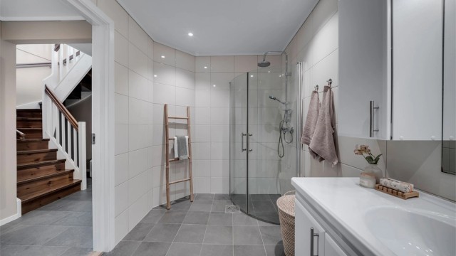 Flislagt bad med behagelig belysning fra downlights og et stilrent dusjhjørne med plassbesparende glassdører.