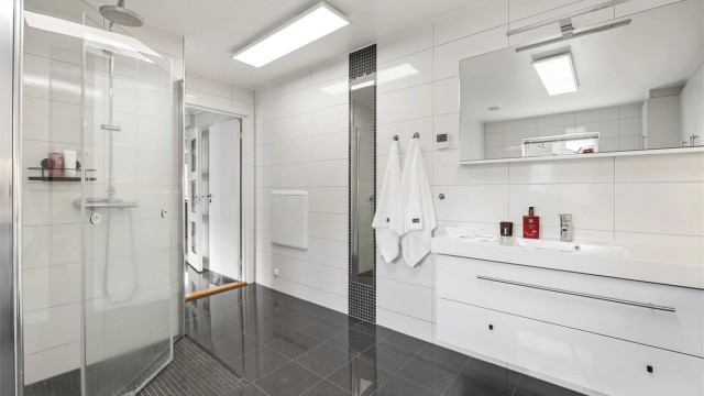 Badet har dusjhjørne med regnfallsdusj og vegghengt toalett.