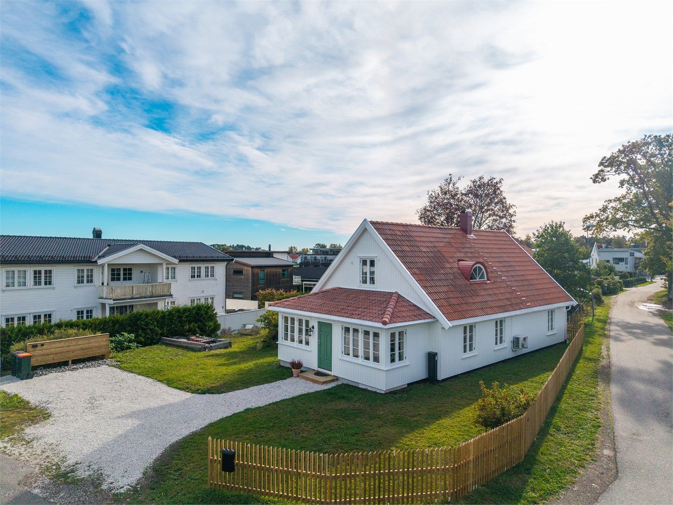 Tomten har en åpen og luftig karakter, samtidig som beplantningen tilfører både grønt preg og den nye stakittgjerde gir en lun ramme rundt boligen.