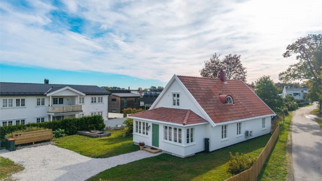 Tomten har en åpen og luftig karakter, samtidig som beplantningen tilfører både grønt preg og den nye stakittgjerde gir en lun ramme rundt boligen.