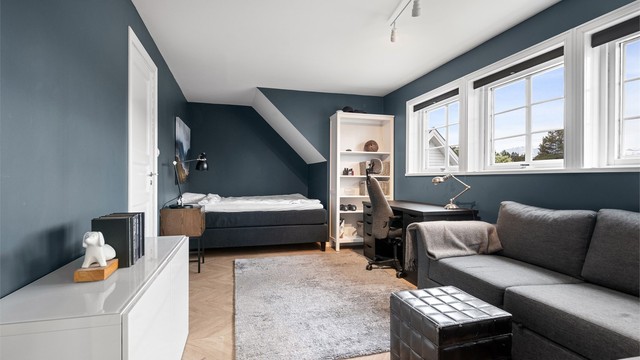Et av soverommene i loftsetasjen, med plass til både seng og en liten sittegruppe.