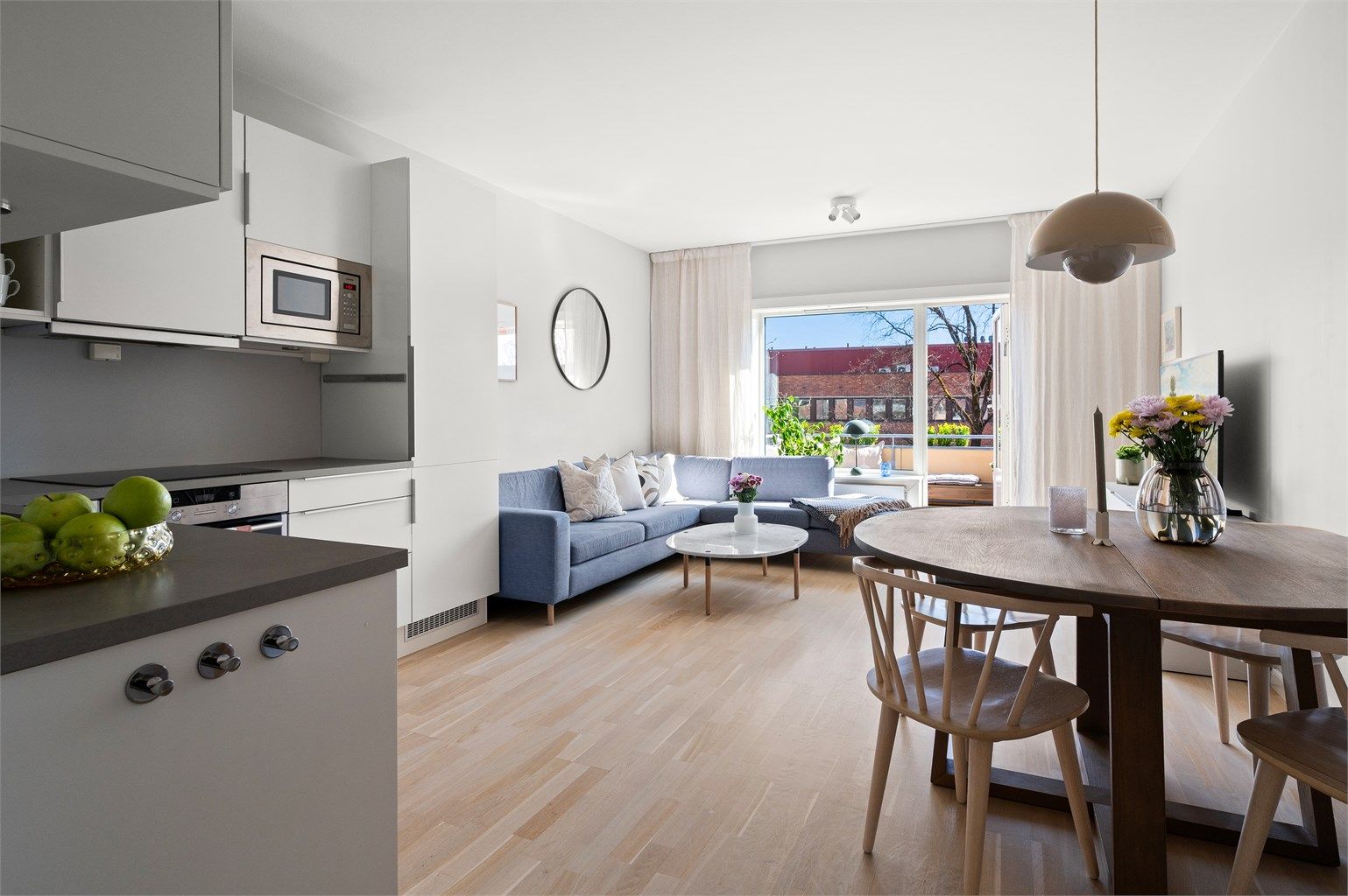 Den åpne løsningen mellom stue og kjøkken skaper en sosial og luftig atmosfære.