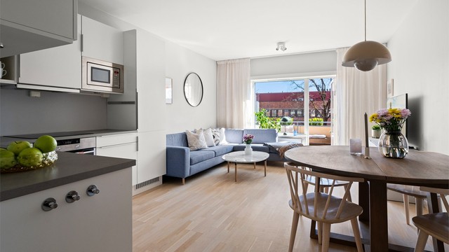 Den åpne løsningen mellom stue og kjøkken skaper en sosial og luftig atmosfære.