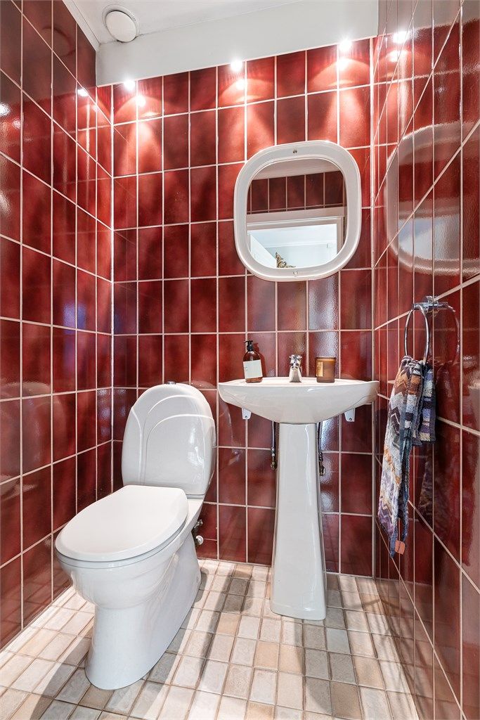 Toalettrom fra byggeår innredet med en enkel servant med ett-greps armatur, samt et gulvstående toalett. Det er avtrekksventil i himlingen.