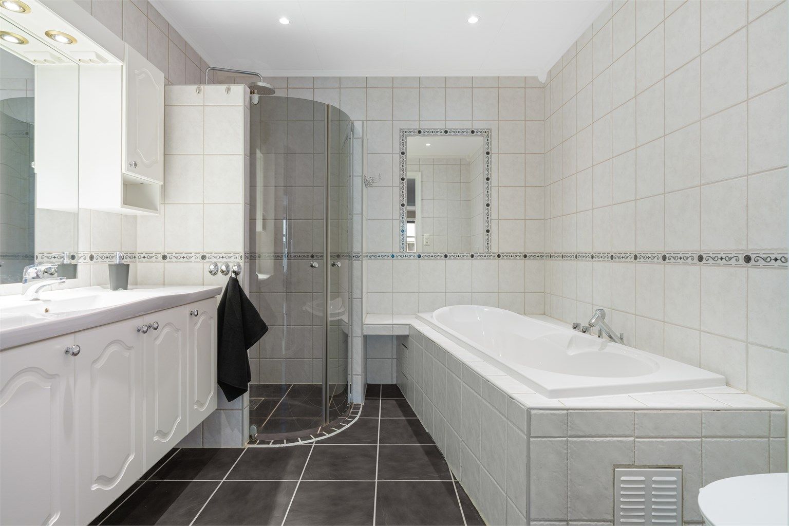 Pent flislagt bad på 6,5 kvm med gulvvarme og downlights i himling. Videre er badet utstyrt med servantskap med overskap og speil med lys, vegghengt toalett, dusjhjørne og badekar.