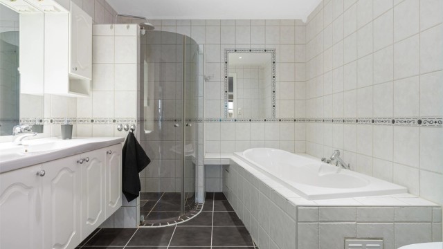 Pent flislagt bad på 6,5 kvm med gulvvarme og downlights i himling. Videre er badet utstyrt med servantskap med overskap og speil med lys, vegghengt toalett, dusjhjørne og badekar.