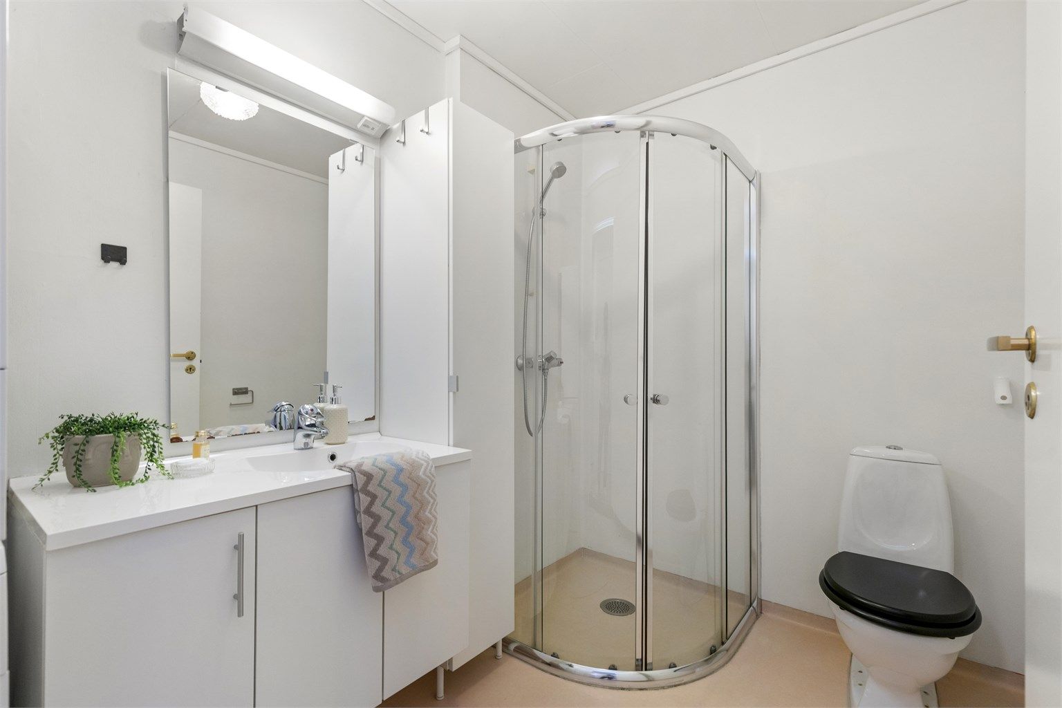 Lyst og funksjonelt bad med dusjkabinett, toalett og god oppbevaringsplass i romslig servantinnredning. Et praktisk og velholdt rom med alt du trenger i hverdagen.