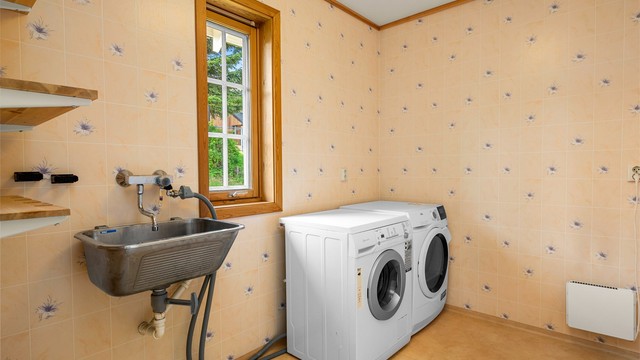 Praktisk, separat vaskerom fra byggeår med utslagsvask og opplegg for vaskemaskin og tørketrommel. Rommet har rikelig med oppbevaringsmuligheter.