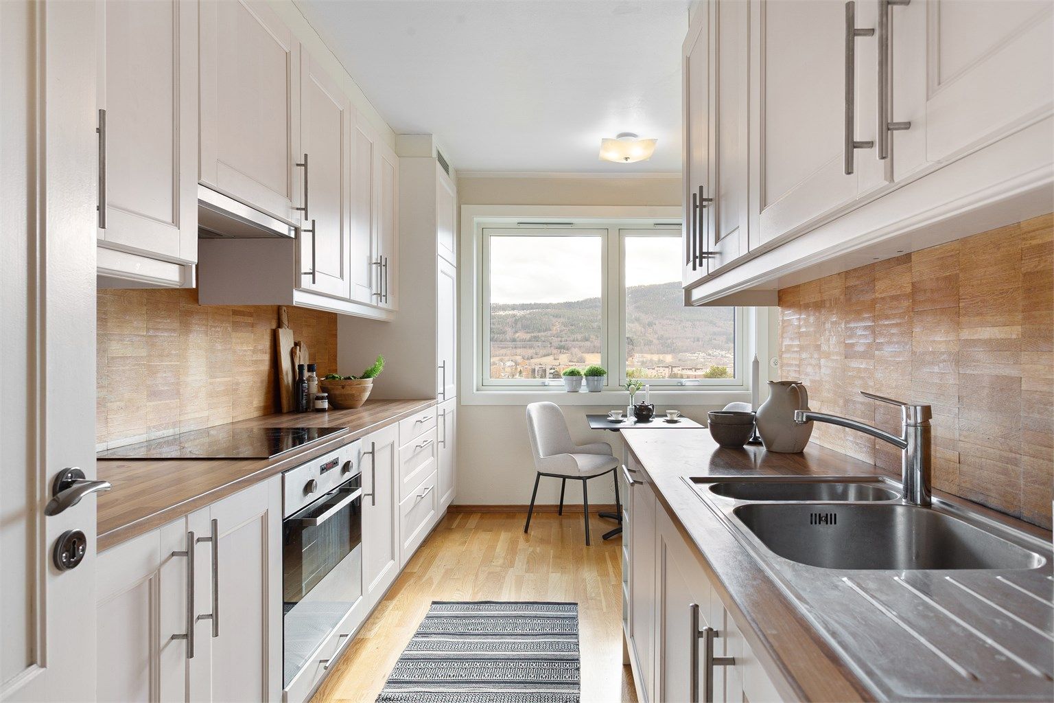 Kjøkken med innredning med profilerte fronter. Benkeplater med laminert overflate og nedfelt kjøkkenvask.