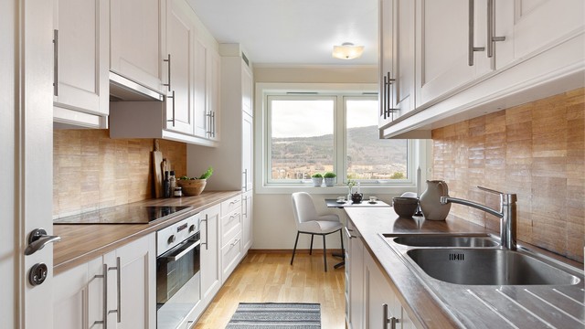 Kjøkken med innredning med profilerte fronter. Benkeplater med laminert overflate og nedfelt kjøkkenvask.