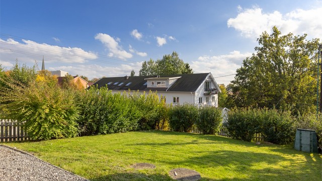 Hagen er opparbeidet med plen, hekk og frodig beplantning.