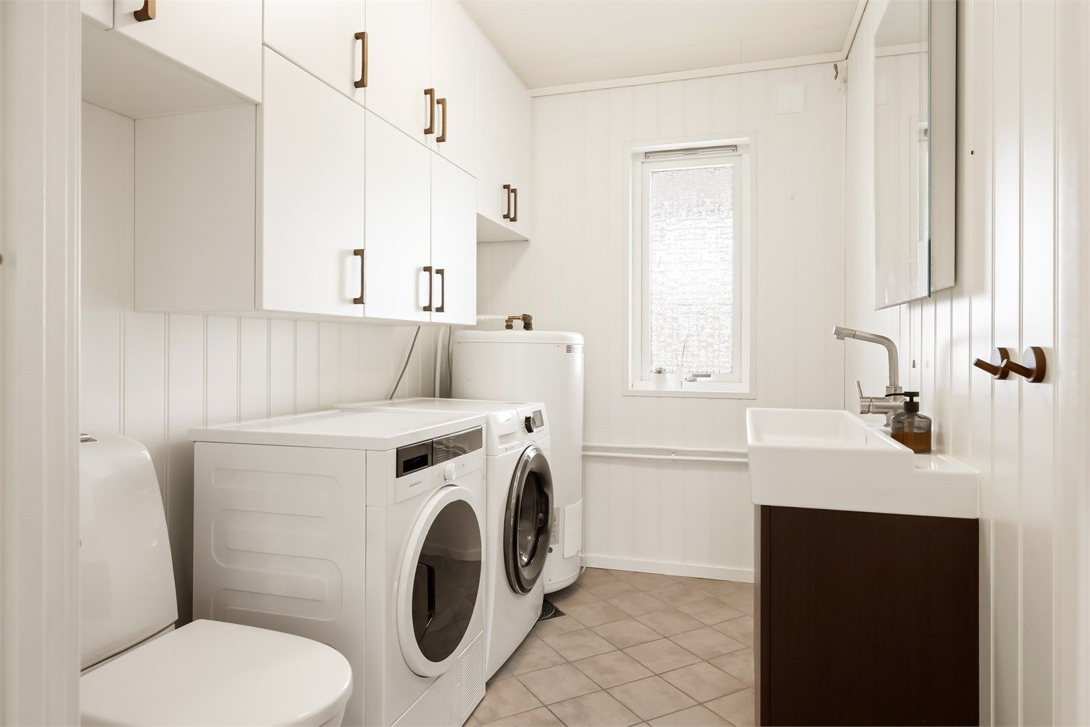 Praktisk separat vaskerom med god oppbevaringsplass. Installert både toalett og servant. Flislagt gulv med varmekabler. 