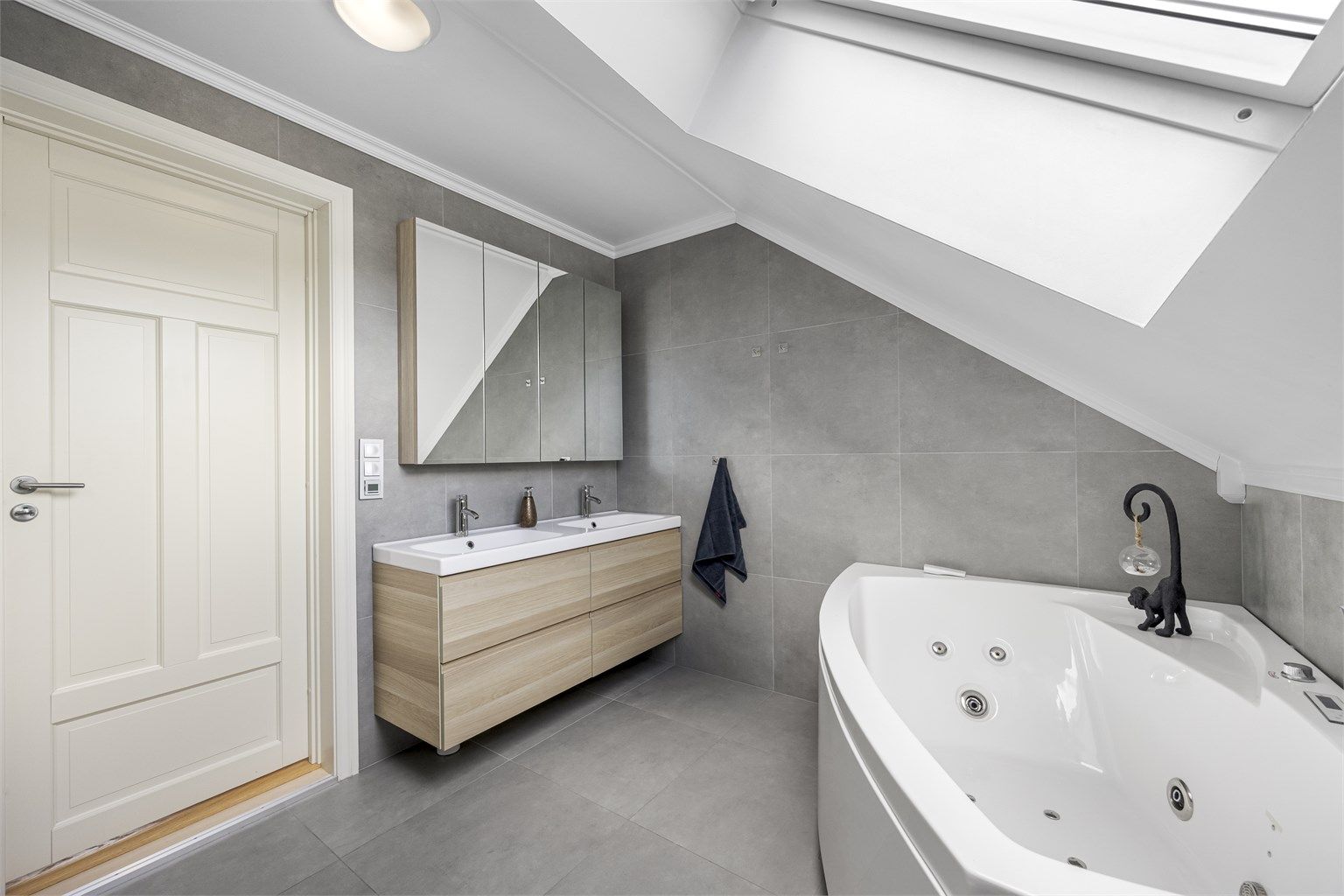 Badet i loftsetasjen har flislagt gulv med gulvvarme, dobbel servant og badekar.