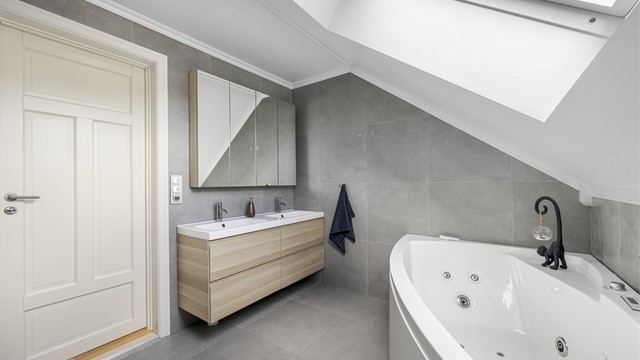 Badet i loftsetasjen har flislagt gulv med gulvvarme, dobbel servant og badekar.